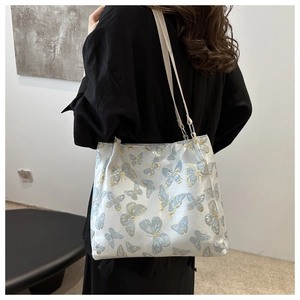 Detailed view of white silk shoulder bag featuring elegant blue and gold butterfly embroidery