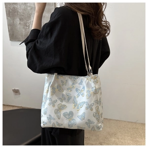 Detail of white tote bag with light blue butterfly embroidery and slim shoulder straps