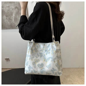 Detail of white satin tote bag with blue butterfly embroidery and silver rings
