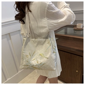 Detail of floral embroidered tote bag with metallic bird motifs and blue leaf patterns