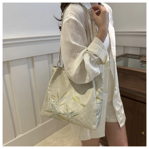 Detail of elegant beige tote bag with floral embroidery on textured fabric