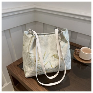 Detailed embroidery of bamboo leaves and birds on a white silk-texture tote bag