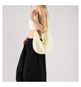 Close-up of pale yellow dumpling bag featuring pleated fabric texture and wide strap
