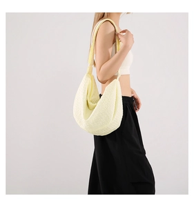 Side view of a pale yellow pleated dumpling bag worn by a model in casual style