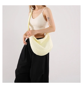 Close-up of a cream pleated hobo bag with woven texture on a model shoulder