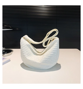 Detail of white crescent bag with unique cloud-like ripple texture and adjustable strap