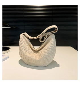 Detailed view of white pleated crescent bag texture on a clean white desk surface