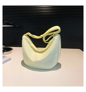 Detail of light yellow half-moon crossbody bag featuring textured bubble fabric material