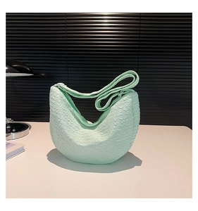 Detail of light green crescent bag showing textured bubble fabric and wide strap