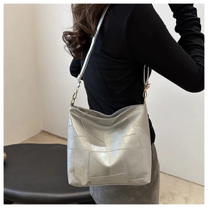 Close-up of silver metallic hobo bag with geometric stitching and golden metal buckles