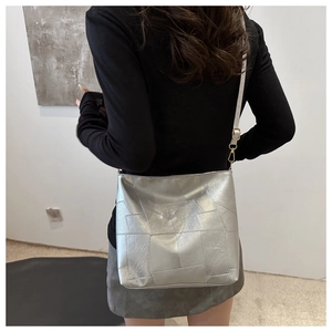 Detail of silver metallic geometric tote bag showing textured leather and shoulder strap