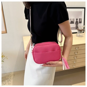 Detail of rose pink litchi grain crossbody bag with ethnic style wide strap and tassel