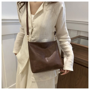 Detail of soft leather shoulder bag in dark coffee with square patchwork and gold hardware