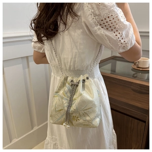 Detail of embroidered jacquard bucket bag with drawstring pearls and silver chain strap