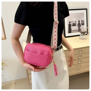 Detail of bright pink pebbled leather crossbody bag with wide geometric woven strap
