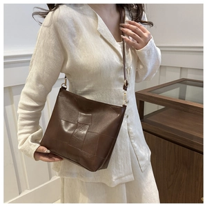 Detailed view of dark brown crossbody bag with woven leather pattern and gold metal hardware