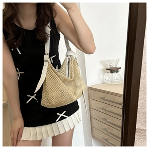 Detail of beige woven straw shoulder bag with white leather strap and metallic buckle