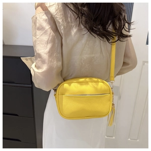 Close-up of bright yellow litchi grain shoulder bag with leather tassel and silver zipper