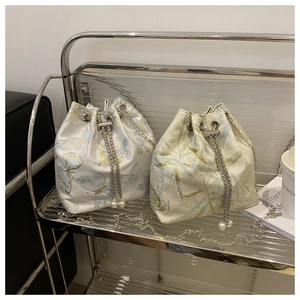 Detail of silk drawstring bucket bags with butterfly patterns and pearl chain straps