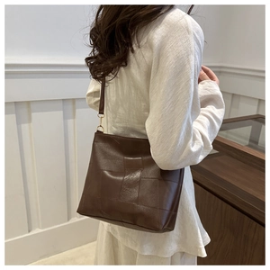 Detail shot of the dark brown PU leather tote bag with square quilted texture and gold buckles