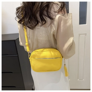 Detail of yellow lychee pattern crossbody bag with fringe tassel charm and zipper