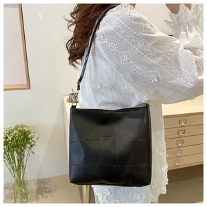 Detail of a large black soft leather tote bag with square patchwork and adjustable strap