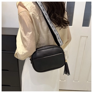 Close-up of black litchi grain crossbody bag with ethnic style wide woven shoulder strap