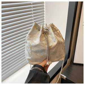 Detail of brocade bucket bag with butterfly embroidery, silver chain, and pearl charms