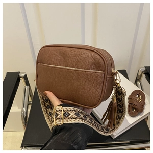 Detail of brown litchi pattern leather crossbody bag with geometric woven shoulder strap