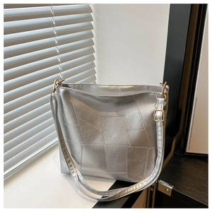 Detail of silver metallic patchwork tote with adjustable strap and golden hardware