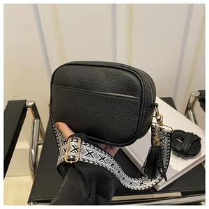 Close-up of black lychee texture crossbody bag with ethnic patterned woven shoulder strap