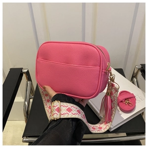 Detail of pink lychee grain crossbody bag with jacquard strap and leather tassel