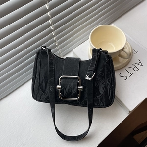 Minimalist black pleated shoulder bag with silver square buckle on a stylish windowsill
