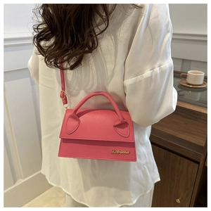 Detail of fuchsia PU leather mini square bag with gold logo shown on model's shoulder