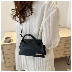 Detail of a black leather mini crossbody bag with gold metal logo and round top handle
