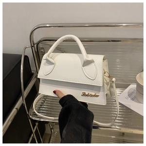 Detail of white PU leather crossbody bag with gold metal logo and cylindrical handle