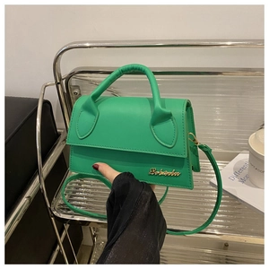 Detail of a bright green mini handbag with gold metal logo and adjustable strap