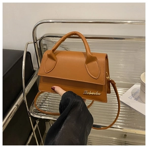 Detailed close-up of brown PU leather shoulder bag with gold metal logo and top handle