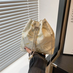Elegant cream drawstring bucket bag with butterfly embroidery and pearl chain strap
