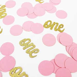 Détail de confettis roses ronds et lettres 'one' dorées pailletées pour 1er anniversaire