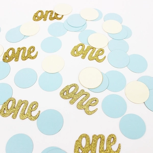 Détail de confettis dorés pailletés 'one' et ronds bleus pour fête de premier anniversaire