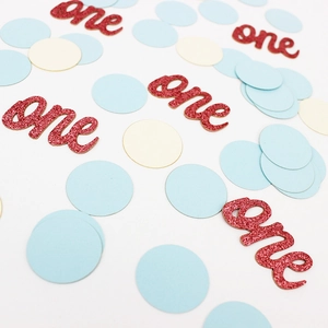 Macro de confettis ronds bleus et blancs avec découpes 'one' en carton pailleté rouge