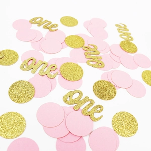 Détail de confettis roses et dorés pailletés avec texte 'one' pour fête de premier anniversaire
