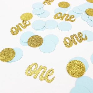 Détail macro de confettis bleus et dorés avec inscription artistique one pour la fête