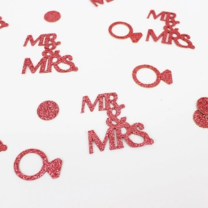 Close-up of red glitter Mr & Mrs confetti with diamond ring shapes for wedding decor