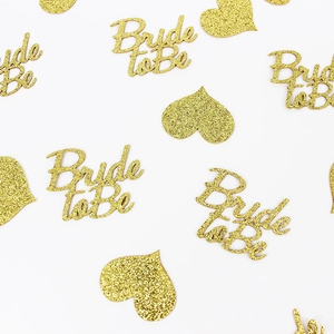 Close-up of gold glitter Bride to Be and heart confetti for wedding table decor