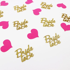 Close-up of gold glitter Bride to Be letters and pink heart confetti for party decor