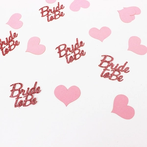 Macro detail of red glitter Bride to Be letters and pink paper hearts confetti for party
