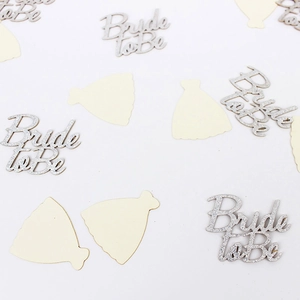 Close-up of silver glitter Bride to Be letters and ivory wedding dress paper confetti