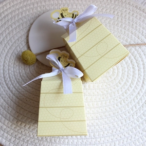 Bee-themed gift boxes with honeycomb patterns and white ribbons for party favors